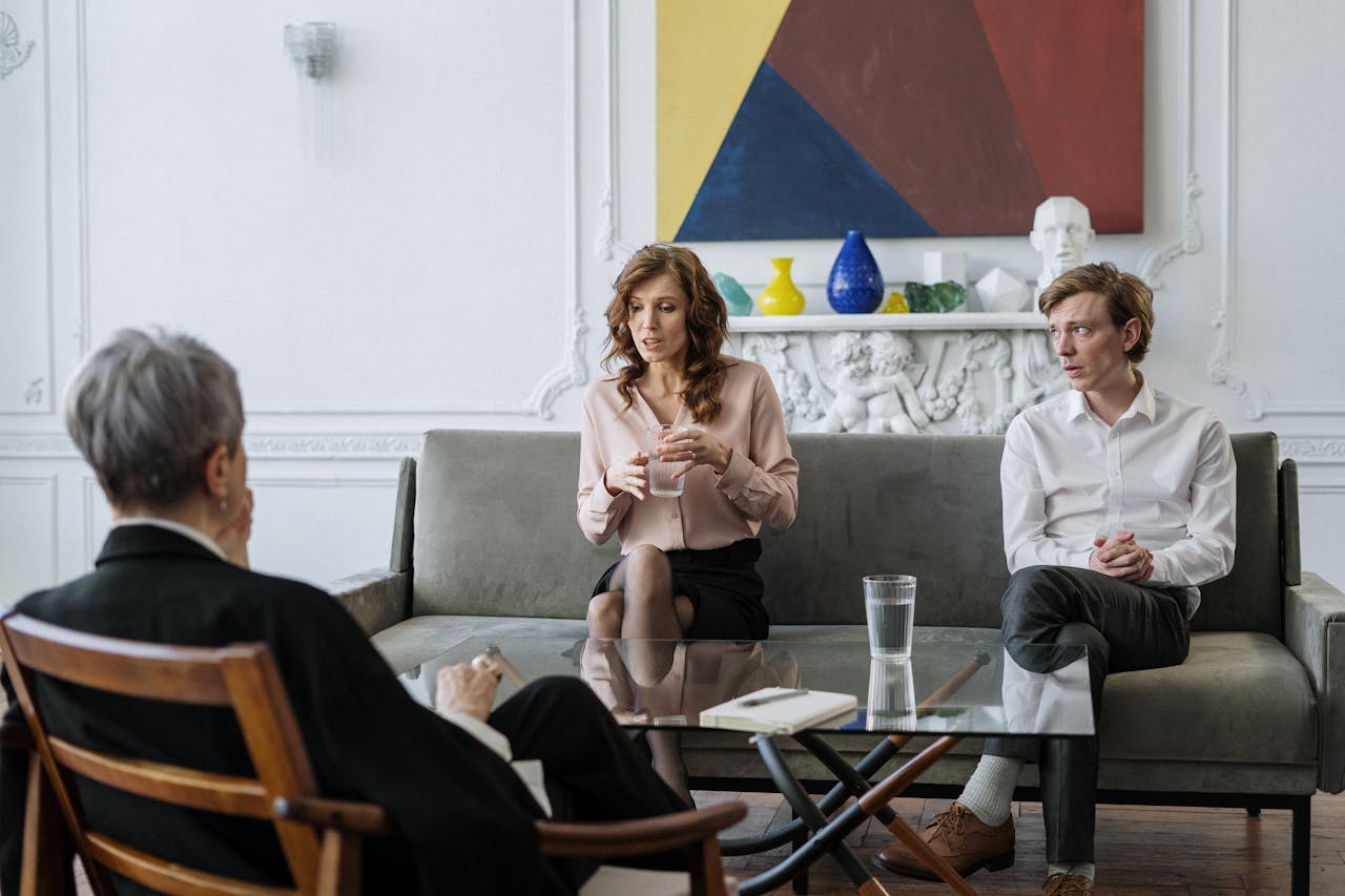Mastering the First Impression: Your intriguing post title goes here A couple conversing with a therapist in a chic, modern office setting.